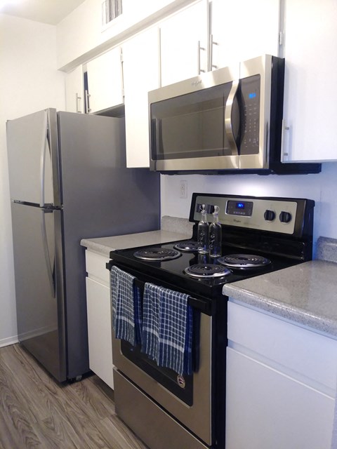 a small kitchen with stainless steel appliances and a stove and microwave