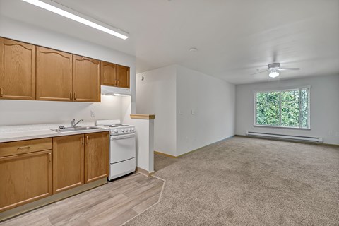 an empty kitchen with wood cabinets and white appliances and a window