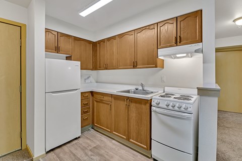 an empty kitchen with white appliances and wooden cabinets