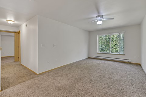 an empty living room with a ceiling fan and a window