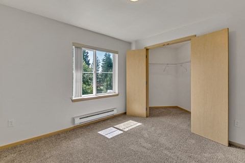 an empty room with a window and a closet