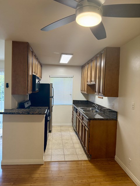 A kitchen with a black refrigerator and wooden cabinets.