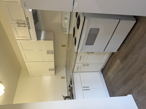 A kitchen with white cabinets and a stainless steel range hood.