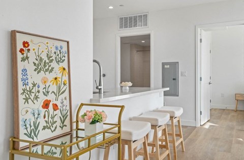 A kitchen with a white counter and a painting of flowers on the wall.