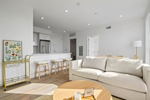 A modern living room with a white sofa and a yellow bar cart.