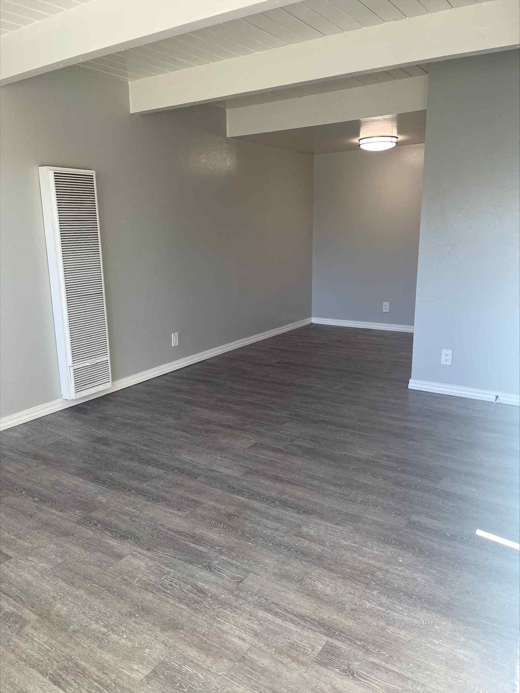 a living room with a hardwood floor and grey walls