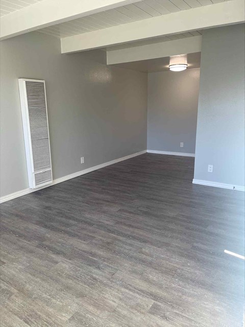 an empty living room with wood floors and grey walls