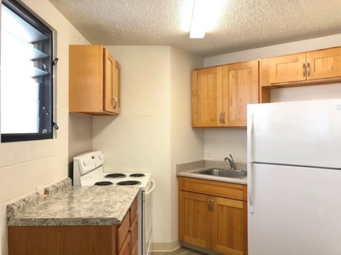 A kitchen with a white refrigerator, a white stove, and wooden cabinets.