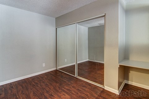 a bedroom with a wood floor and a mirrored closet