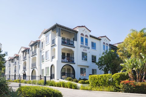 A white building with balconies and a black fence in front.