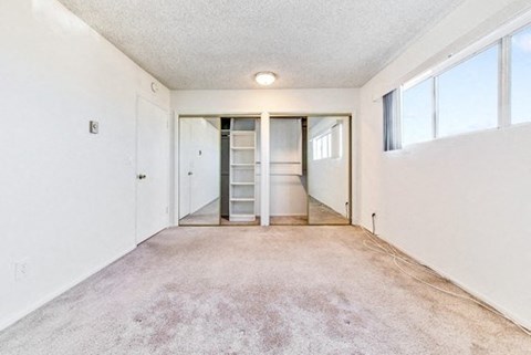 A spacious room with white walls and a carpeted floor.