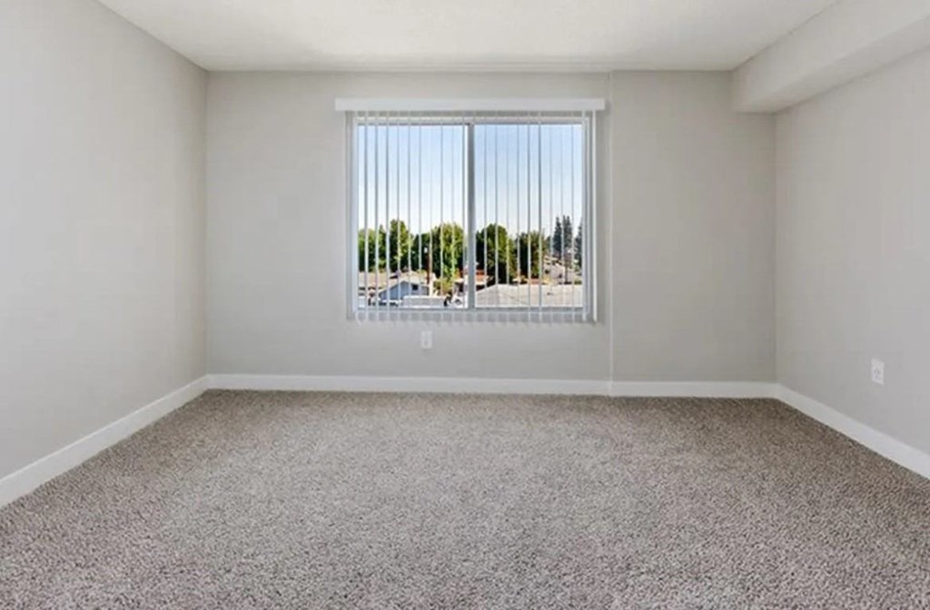 an empty living room with a large window and carpet