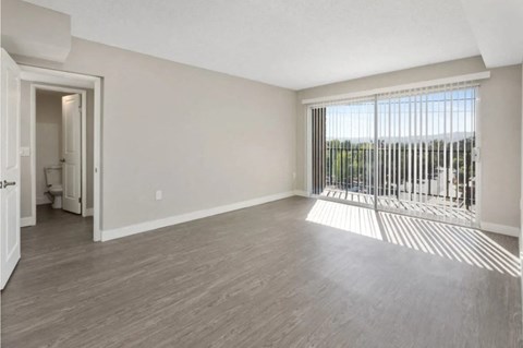 an empty living room with a large window and wood flooring
