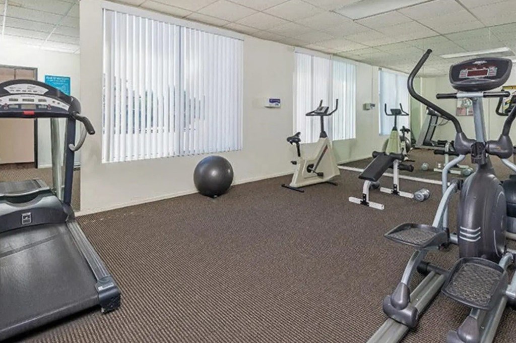 a gym with various exercise equipment on the floor and a window