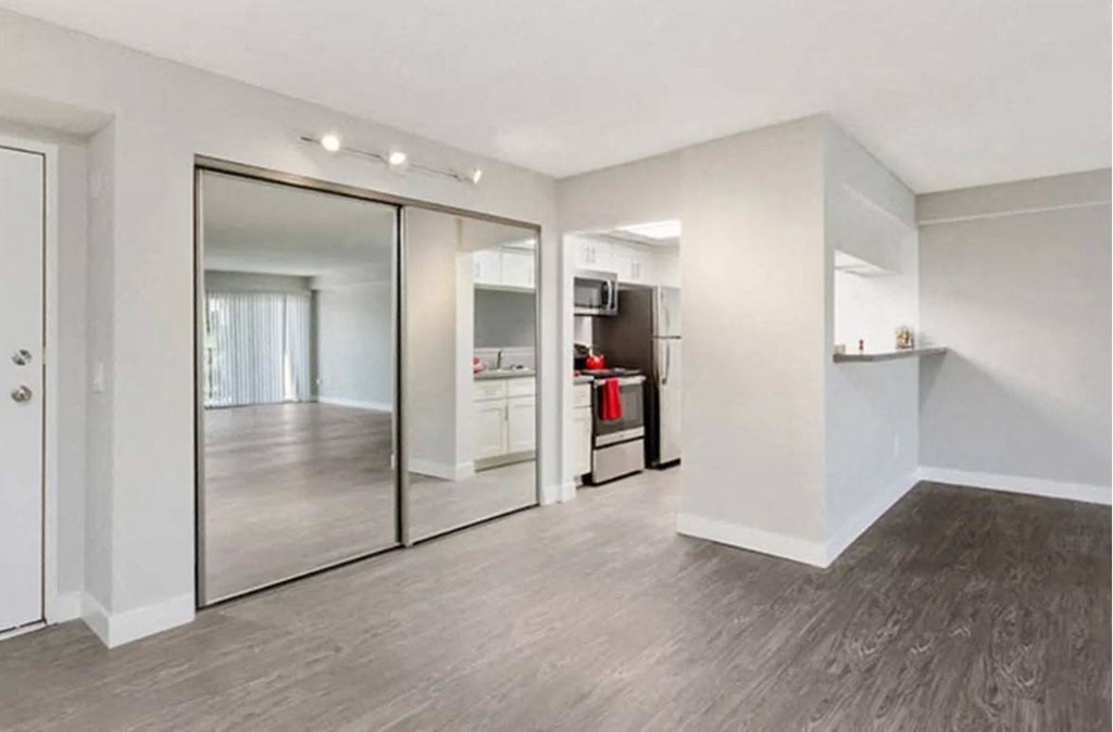 an empty living room with a large mirror and a kitchen