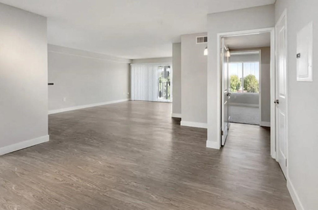 an empty living room with white walls and wood floors