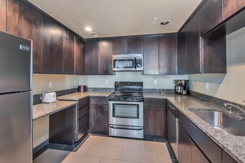 A modern kitchen with dark brown cabinets and stainless steel appliances.