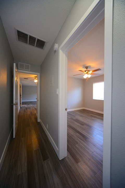 an empty living room with wood floors and a ceiling fan
