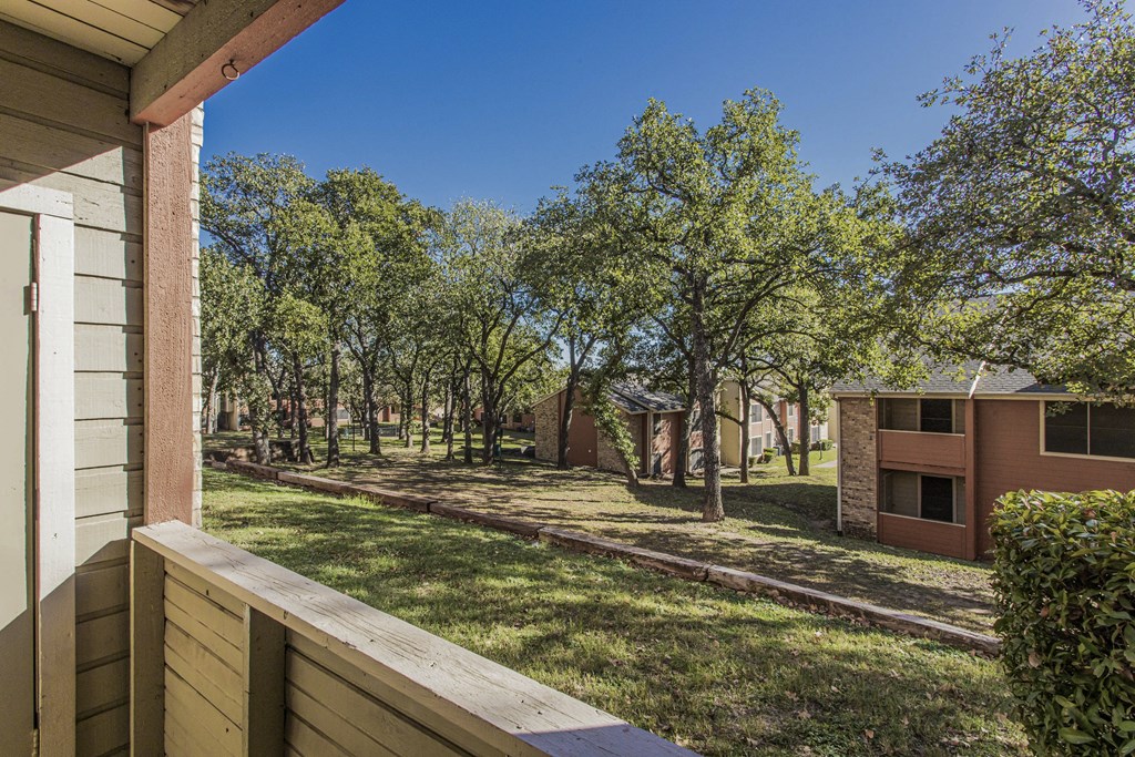 the view from the deck of a house with a yard and trees