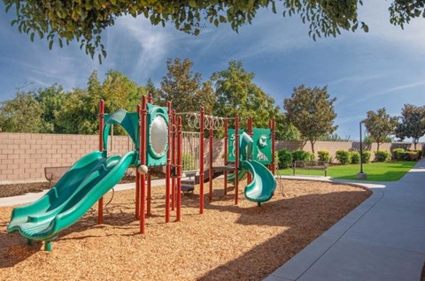 A playground with a green slide and a red structure.