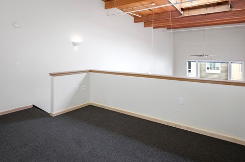 A room with a carpeted floor and a window with blinds.