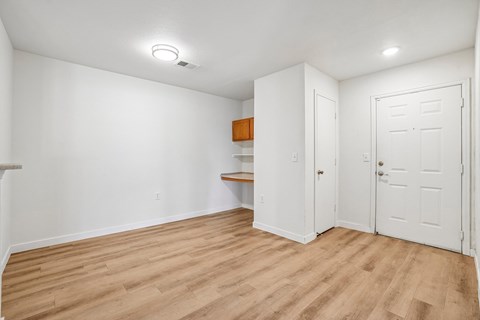 A room with white walls and wooden flooring with a small brown cabinet.