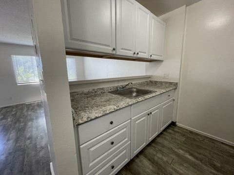 A kitchen with white cabinets and a granite countertop.