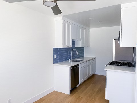 a renovated kitchen with white cabinets and a blue tile backsplash