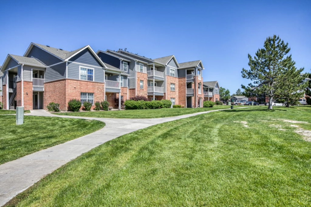A row of apartment buildings with a grassy area in front.