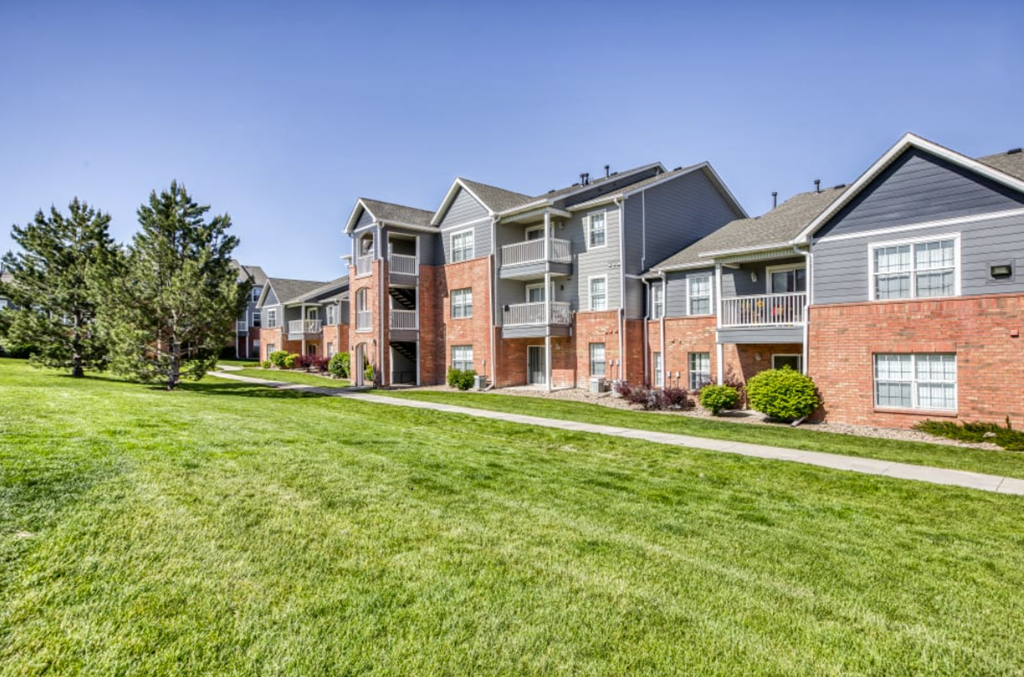 A row of modern brick apartment buildings with green lawns in front.