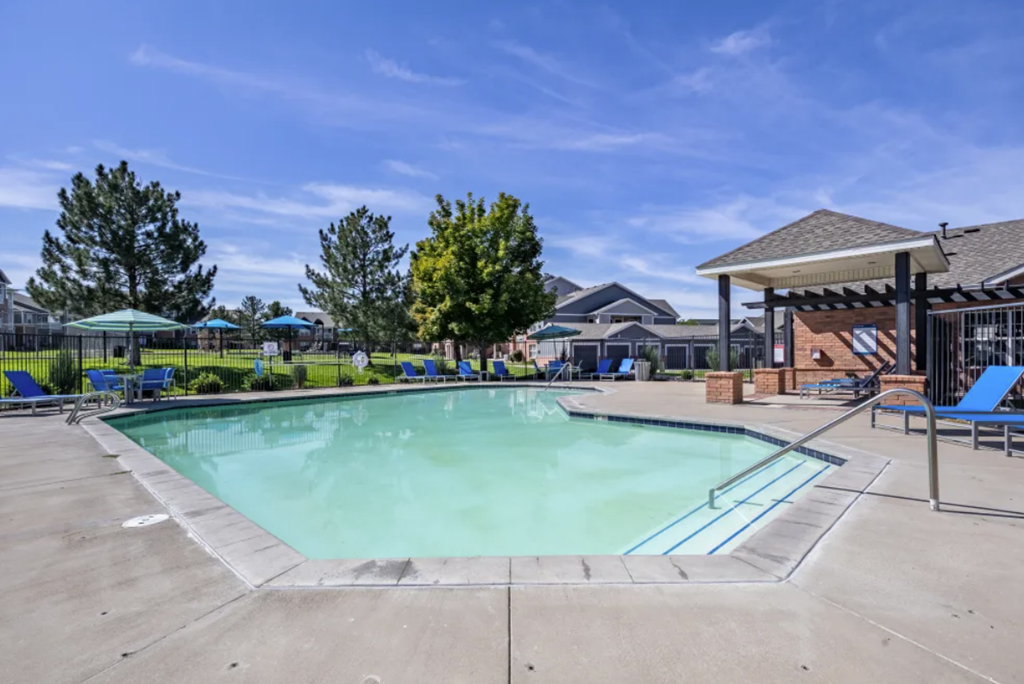 A large outdoor swimming pool with a pavilion and lounge chairs.