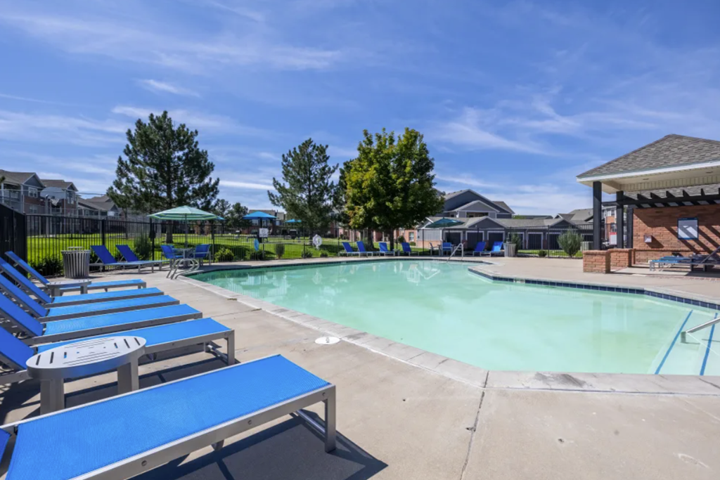 A pool area with blue loungers and a clear sky.