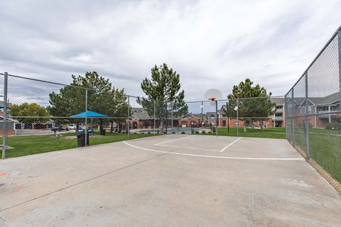 A basketball court is surrounded by a chain link fence.