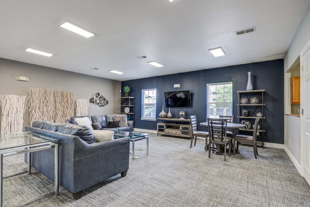 A living room with a grey couch and a glass coffee table.