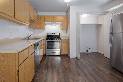 A kitchen with wooden cabinets and a stainless steel refrigerator.