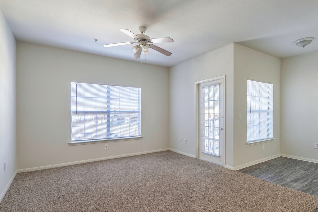 a living room with a ceiling fan and two windows
