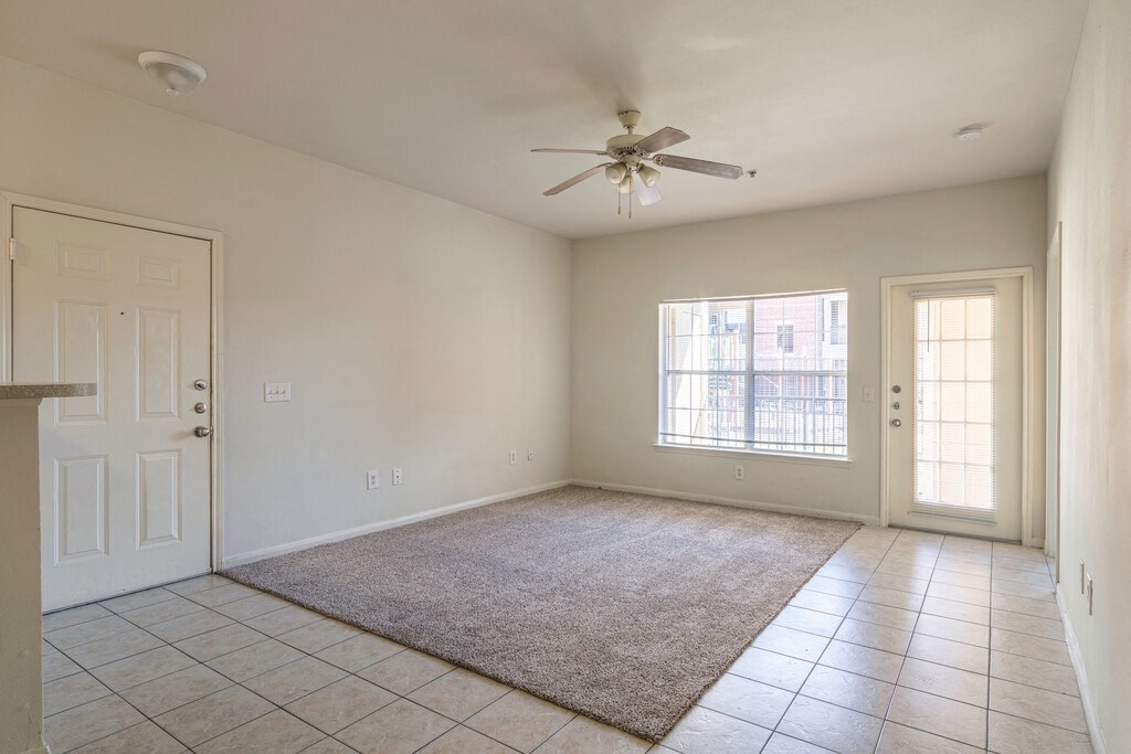 an empty living room with a ceiling fan