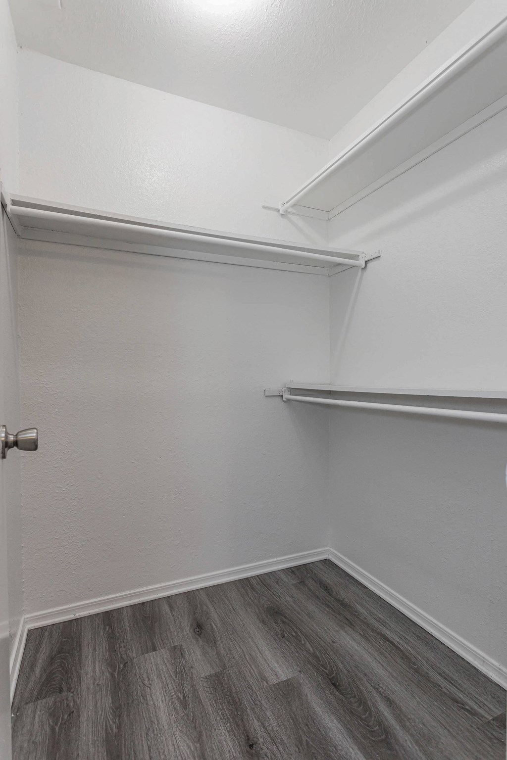 the closet in a small room with white walls and wood flooring