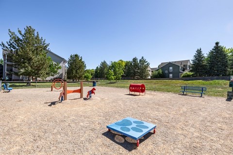A playground with a blue sandbox in the foreground and a red slide in the background.