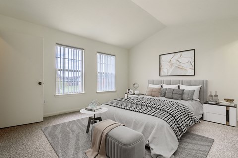 A bedroom with a large bed and a window with blinds.