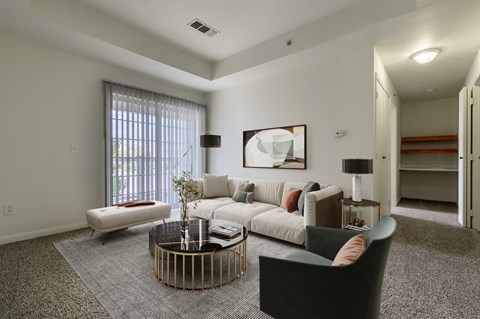 A living room with a grey carpet and a white sofa.