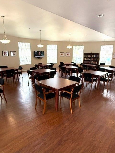 A room with tables and chairs and a television on the wall.