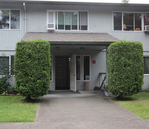 the front door of a house with two hedges in front of it