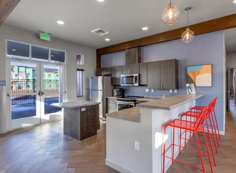 A kitchen with a white island and red chairs.