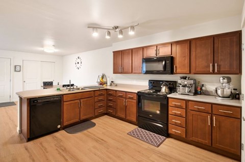 A kitchen with wooden cabinets and black appliances.
