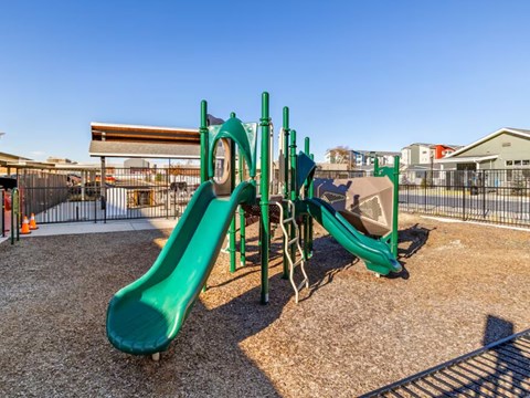 A playground with a green slide and a wooden structure.