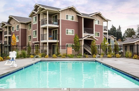 A large apartment complex with a pool in front.