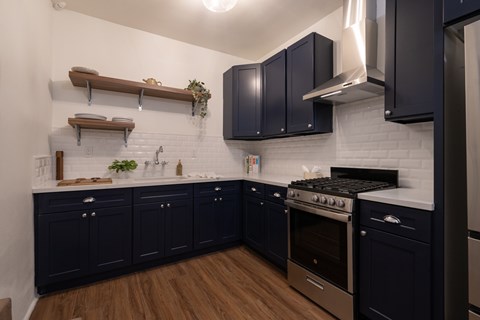 A kitchen with dark blue cabinets and a white subway tile backsplash.