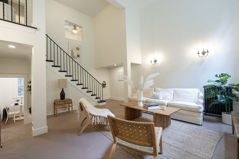 A living room with a white couch and a wooden chair.
