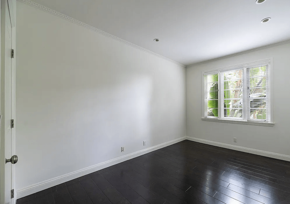 a bedroom with white walls and a window